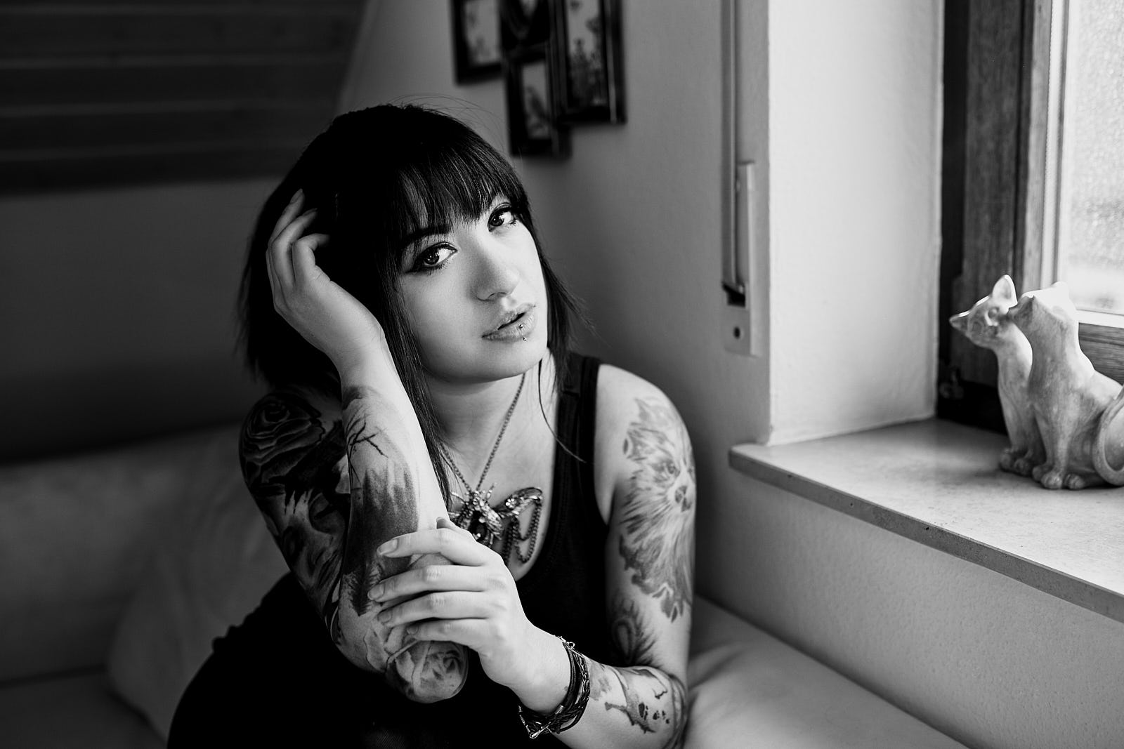 Portrait von Tattoomodel Kiri die auf dem Sofa am Fenster sitzt