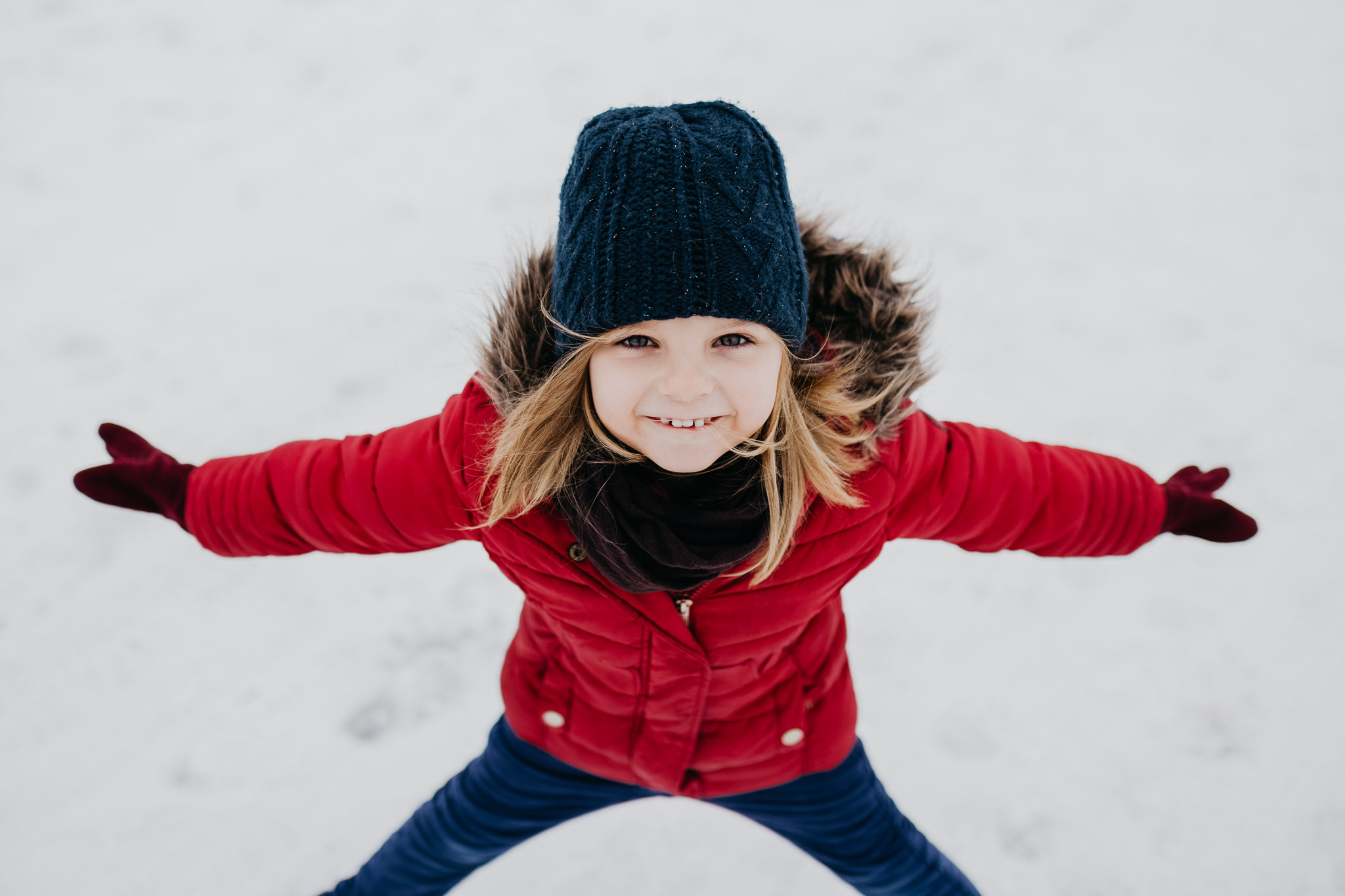 kleines Mädchen in roter Jacke im Schnee