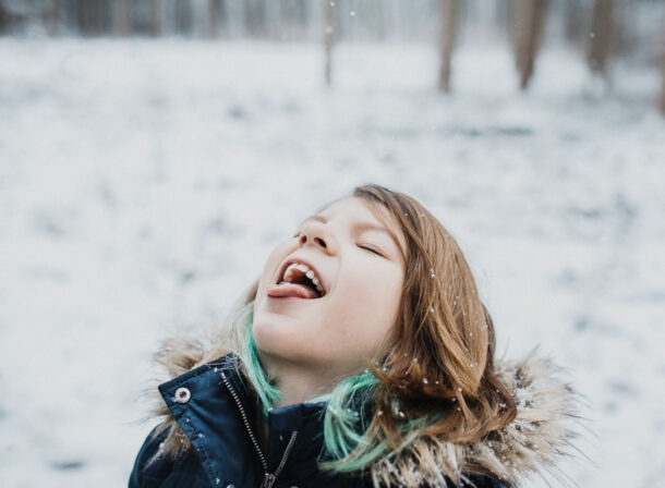 Mädchen fängt mit der Zunge Schneeflocken