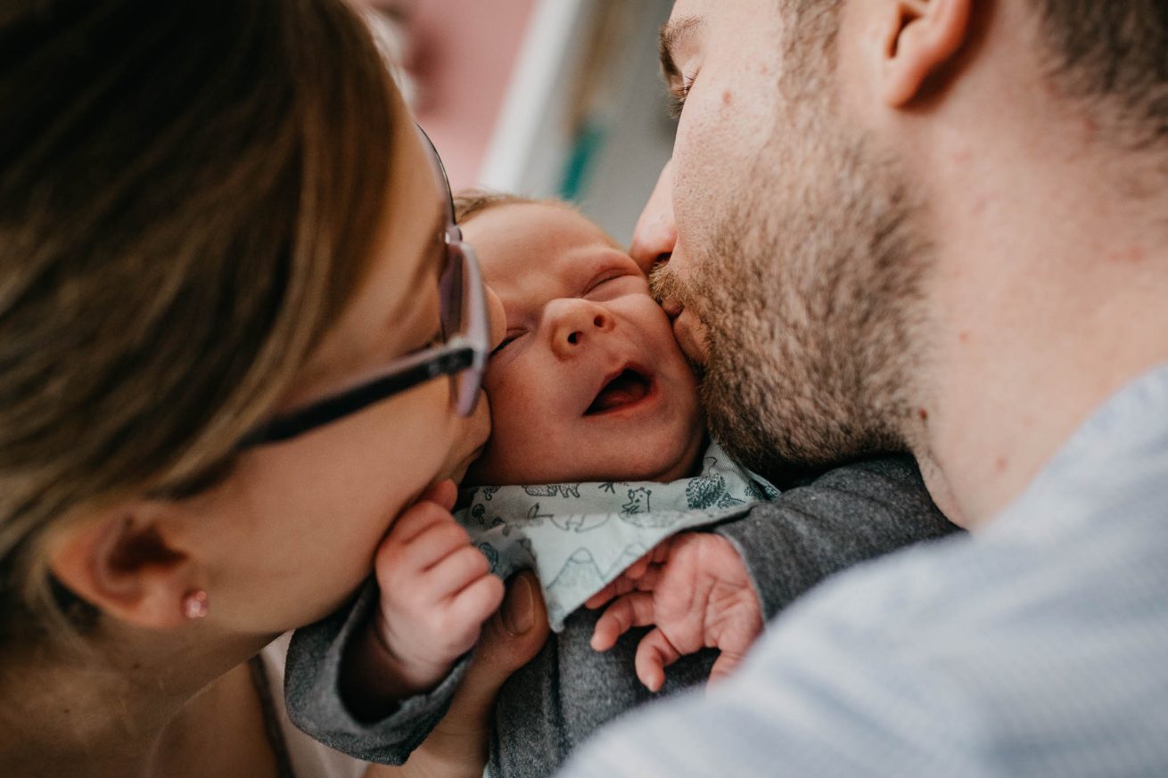 Eltern geben dem Baby ein Kuss auf die Wange